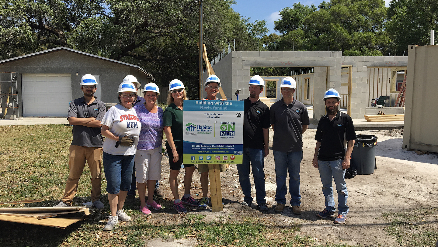 VIBE team standing behind Habitat for Humanity sign for the Neris family's home